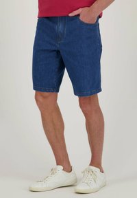 Donkerblauwe denim shorts met een rechte snit, voorzien van riemlussen en een enkele voorkantzak, gedragen met witte sneakers.