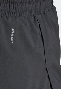 Černé sportovní šortky z lehké tkaniny. Mají elastický pas a na boku nápis „AEROREADY“. Hladká textura.