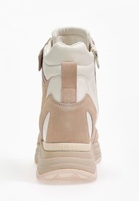 High-top sneaker in beige and cream, featuring suede and leather materials, a smooth texture, and rear logo detail. Zipper accent on side.
