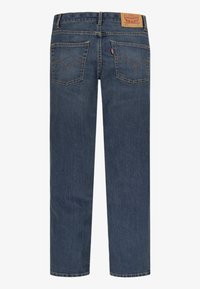 Vue arrière d’un jean en denim bleu foncé avec deux poches arrière, des coutures orange et une étiquette de marque en cuir marron sur la ceinture.