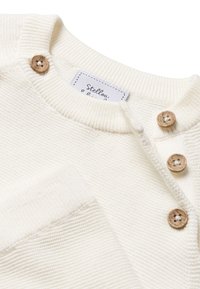 Witte gebreide trui met een ribbelkraag, voorzien van drie houten knopen en een label met de naam "Stellou." Zacht, gestructureerd materiaal met een casual pasvorm.