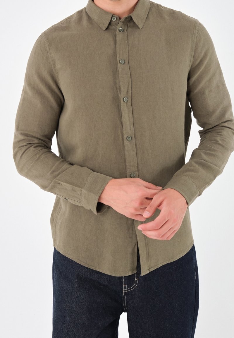 Camicia button-up verde oliva realizzata in tessuto testurizzato, con colletto e maniche lunghe, orlo dritto e polsini con bottoni.