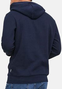Marineblauer Hoodie mit Kordelzug und Kängurutasche, versehen mit gerippten Bündchen und Saum für eine strukturierte Optik. Die Rückansicht zeigt die Nahtdetails.