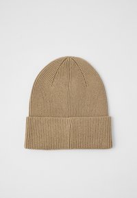 Adīta cepure gaiši brūnā krāsā. Iespējama ribota faktūra ar salocītu apkakli un noapaļotu augšdaļu. Mīksts materiāls siltumam.