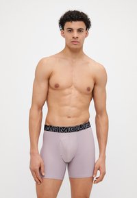 Hellblaue Boxershorts aus elastischem Stoff, mit einem schwarzen Bund, auf dem in Weiß "ARMOUR" gedruckt ist, und einem unterstützenden Frontdesign.