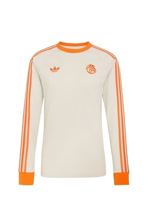 Valge pika varrukaga spordisärk oranži krae, mansettide, kolme oranži triibuga varrukatel ja kahe oranži logoga rinnal.