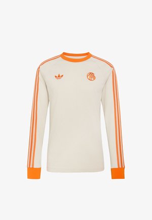 Valge pika varrukaga spordisärk oranži krae, mansettide, kolme oranži triibuga varrukatel ja kahe oranži logoga rinnal.