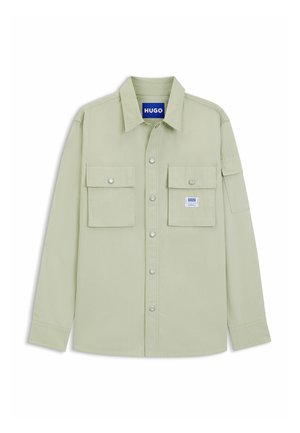 Light green button-up shirt made of textured fabric. Features two chest pockets and a tag with "HUGO" logo on the collar.