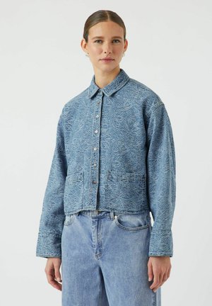 Korte denim jas in lichtblauw met reliëf bloemenpatroon, knoopsluiting en twee voorzakken. Gepaard met lichtblauwe jeans.