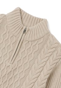 Maglione beige a coste lavorato a maglia con colletto alto e zip a metà. Presenta motivi testurizzati e un tessuto a maglia liscia. Zip metallica discreta.