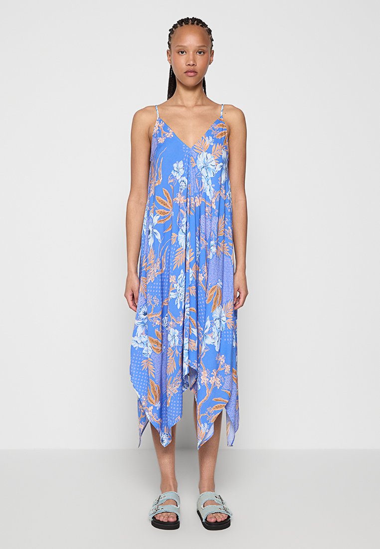 Vestido floral azul con tirantes finos, que presenta un diseño en capas y un dobladillo asimétrico. La tela exhibe varios patrones florales y de puntos.