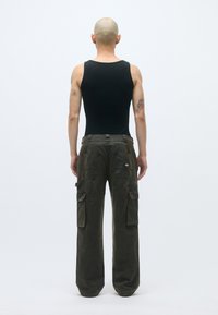 Παντελόνια cargo σε σκούρο ελαιόχρωμο, με πλαϊνές τσέπες, χαλαρή εφαρμογή, ορατές ραφές και υφή υφάσματος. Εμφανίζεται η πίσω όψη.