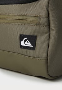 Green fabric pouch with a textured surface, featuring a black and white logo patch and a top zippered closure.