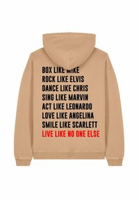 Felpa beige con cappuccio, caratterizzata da testo nero e rosso sul retro con frasi motivazionali. Include un cappuccio e polsini e orlo a coste.