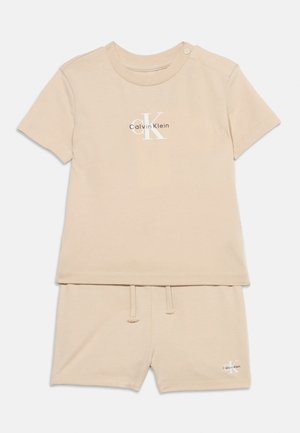 Ensemble bébé beige Calvin Klein comprenant un haut à manches courtes avec bouton sur l'épaule et un short assorti avec taille à cordon.