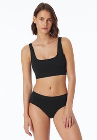 Bralette nera in cotone con scollatura quadrata e spalline larghe, abbinata a mutande a vita alta coordinate con una cintura morbida.