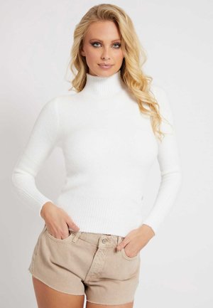 Maglione bianco a collo alto in maglia con texture a coste, maniche lunghe e design aderente. Abbinato a pantaloni shorts in denim beige.
