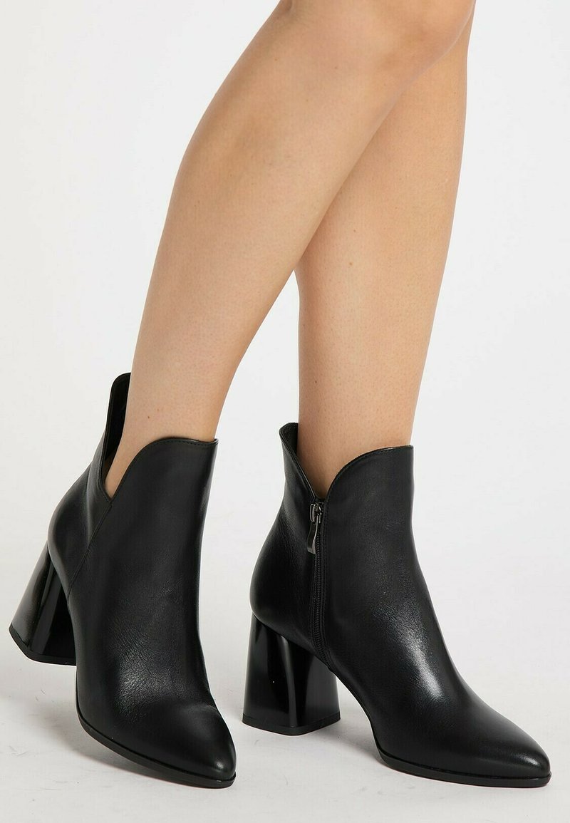 Botine negre din piele cu vârful ascuțit, fermoar pe lateral și toc gros, lucios. Designul include un detaliu decupat la gleznă.