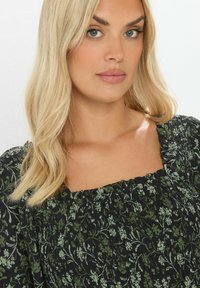 Vihreä kukkakuosiset mekko, jossa on kerrostettu neliönmuotoinen kaula-aukko ja puffihihat, valmistettu kevyestä kankaasta, jossa on teksturoitu pinta.