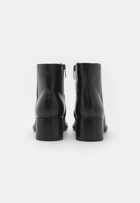 Black leather ankle boots with a smooth finish, rounded toe, side zippers, and a chunky heel. Durable design with minimalist style.