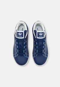 Dark blue leather sneakers with white accents, round toe, perforated sides, and navy laces. Features a branded tongue and cushioned interior.