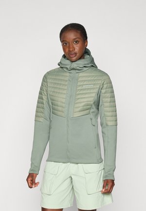 Lys grøn zip-up jakke med hætte, der har quiltet polstret øverste del og glat nederste sektion. Inkluderer sidelommer og logo-detalje.