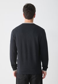 Dark navy sweatshirt with long sleeves, ribbed cuffs, and collar featuring a white accent stripe. Smooth texture, relaxed fit, and minimalist design.