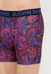 Ανδρικά μποξέρ σλιπ με έντονο σχέδιο paisley σε κόκκινο, μπλε και μαύρο. Ελαστική μέση με λογότυπο "BJÖRN BORG". Λείος, εφαρμοστός σχεδιασμός.
