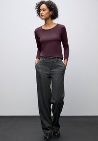 Maroon long-sleeve top paired with gray wide-leg trousers featuring a subtle pattern and a button at the waist. Black shoes complete the look.