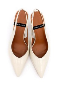 Tacchi slingback bianchi in pelle con punta affilata e design ritagliato. Soletta marrone con etichetta del marchio visibile. Texture liscia.