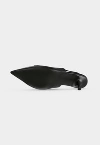 Chaussure à talon haut noire à bout pointu vue de la semelle, montrant un talon aiguille fin et un cuir lisse.