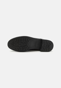 Black rubber shoe sole with a textured pattern featuring traction grips and a rounded toe. Brand name "Clarks" embossed on the side.
