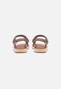 Brown leather sandals with wide straps, open back, and light, textured rubber soles. Features adjustable straps for fit.