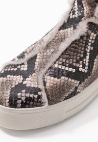 Tenisky se strukturovaným černobrným hadím potiskem, s jemným šedým kožíškem na okraji a silnou bílou gumovou podrážkou.
