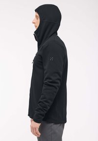 Giacca con cappuccio nera realizzata in un tessuto morbido e stretch. Presenta una zip, cuciture piatte e un design aderente.