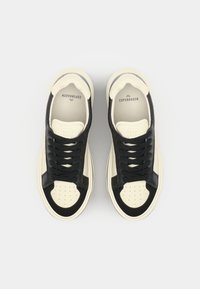 Svart og kremfargede skinn-sneakers med avrunde tær, perforert front, flate lisser og kontrastdetaljer. Logo på tungen og i sålen.
