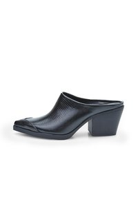 Mule hitam dari kulit dengan ujung terbuka, memiliki permukaan yang tekstur, desain ujung runcing, dan tumit blok. Interior yang halus dengan sisi yang melengkung.