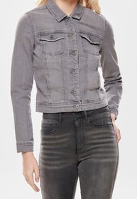 Chaqueta de mezclilla gris con cuello tipo camisa, cierre de botones, dos bolsillos en el pecho, mangas largas y un diseño corto.