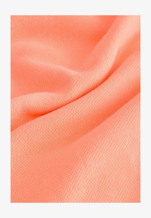 Svijetlo koraljna tkanina s glatkom, pletenom teksturom i finim rebrima. Materijal se nježno oblaže, stvarajući blage valove.