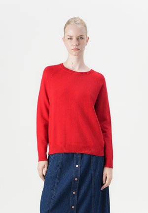 Red knit sweater with a crew neck, ribbed cuffs and hem, and relaxed fit. Paired with a denim skirt featuring buttons down the front.