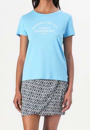 Vaaleansininen lyhythihainen puuvillainen t-paita, jossa valkoinen teksti. Yhdistetty polvipituiseen hameeseen, jossa laivastonsininen ja valkoinen geometrinen kuvio.