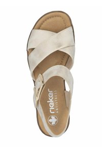 Beige suede sandal with crisscross straps, adjustable metallic buckle, soft cushioned insole, and a rounded toe design.