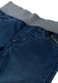 Pantalones de mezclilla de color azul oscuro, con una cinturilla acanalada gris y bolsillos estándar, mostrando un acabado textil suave.