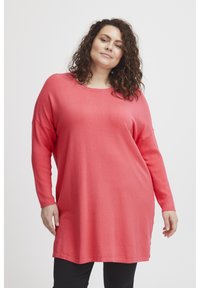 Maglione corallo a maniche lunghe realizzato in materiale morbido, con una vestibilità ampia, scollo rotondo e fessure laterali per facilitare il movimento.