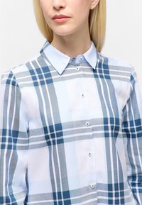 Skjorte med knapfront i et blåt og gråt plaidmønster. Lavet af letvægtsstof med krave og frontlukning med knapper.