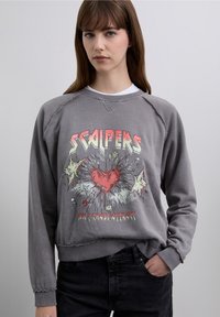 Grey sweatshirt with a distressed texture, featuring a colorful graphic design of a heart and text "SCAPERS" and "DON'T CHASE ATTRACT."
