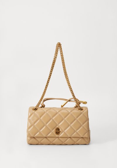 Sac à main beige matelassé avec une bandoulière en chaîne dorée, texture en cuir lisse et accent logo à l'avant. Forme rectangulaire avec un design structuré.