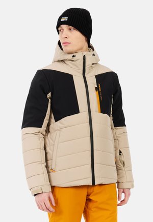 Beige en zwarte gewatteerde jas met een ritszak, met een capuchon, geborduurd ontwerp en oranje accenten. Draagt een oranje onderrok.