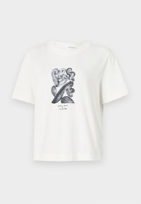 Hvit bomull t-skjorte med et svart abstrakt design med buede former og teksten "nous vous". Korte ermer og rund hals.