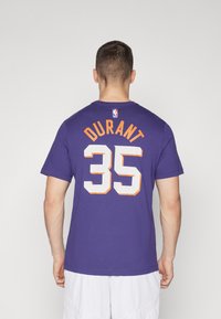 Paarse katoenen T-shirt met korte mouwen, met witte kunststof cijfers "35" en "DURANT" in oranje letters op de achterkant. NBA-logo boven de tekst.